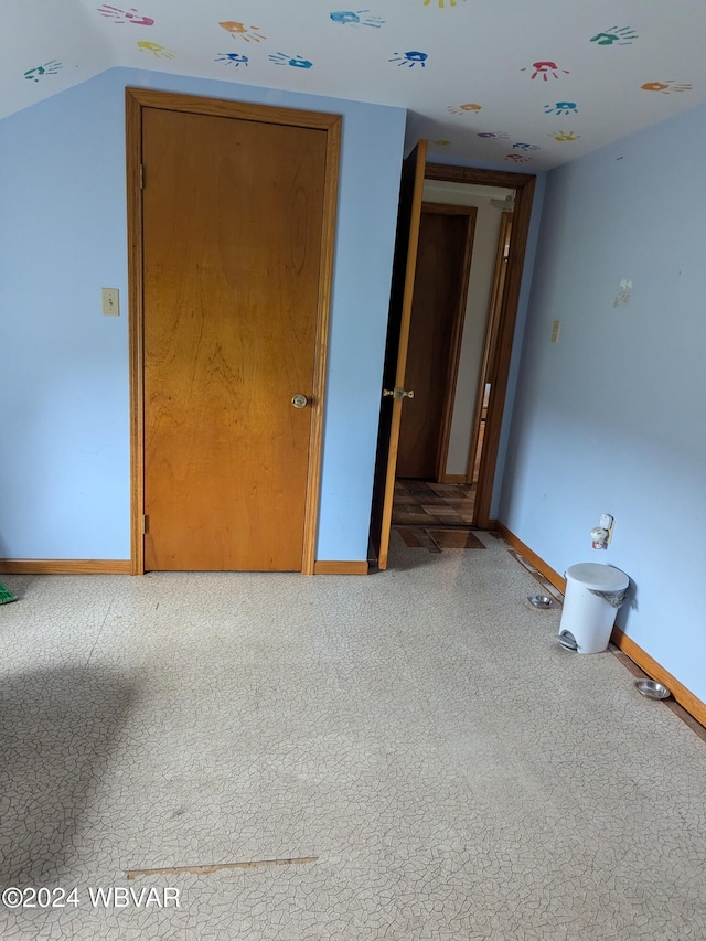 unfurnished room featuring carpet and vaulted ceiling