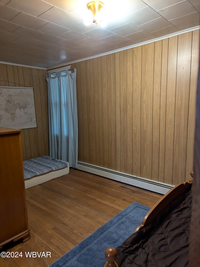 unfurnished bedroom featuring wooden walls, hardwood / wood-style floors, and a baseboard radiator