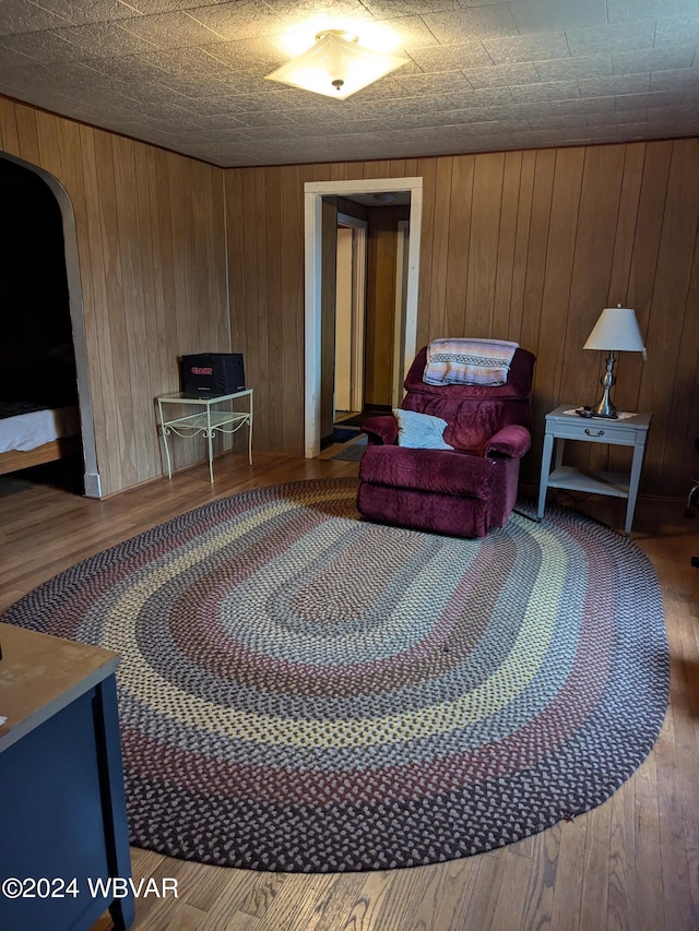 living room featuring hardwood / wood-style flooring, a textured ceiling, and wooden walls