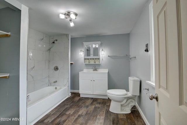 full bathroom with hardwood / wood-style floors, tiled shower / bath combo, toilet, and vanity