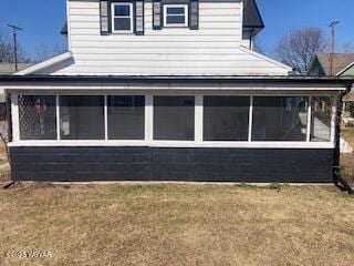 view of side of home featuring a lawn and a sunroom