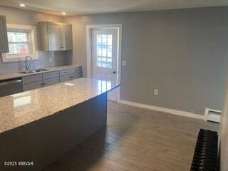 kitchen featuring a sink, baseboards, gray cabinetry, and dark wood-style floors