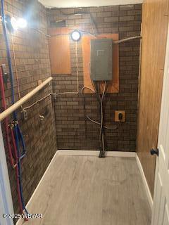 bathroom featuring wood finished floors and brick wall