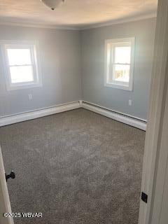 carpeted empty room featuring a baseboard heating unit, crown molding, and baseboards