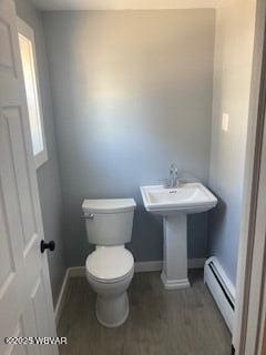 bathroom featuring toilet, a baseboard heating unit, baseboards, and wood finished floors