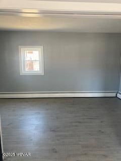 spare room with a baseboard heating unit and wood finished floors