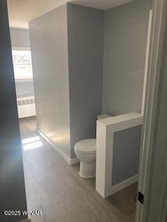 bathroom with radiator, toilet, and baseboards