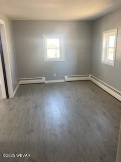 spare room featuring baseboard heating, plenty of natural light, and wood finished floors