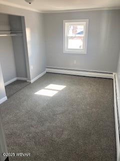 unfurnished bedroom with crown molding, a baseboard heating unit, baseboards, carpet floors, and a closet