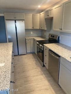 kitchen with stainless steel appliances, light stone countertops, light wood-style flooring, and gray cabinets