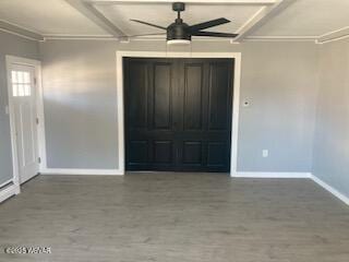 interior space with baseboards, beam ceiling, wood finished floors, and a ceiling fan