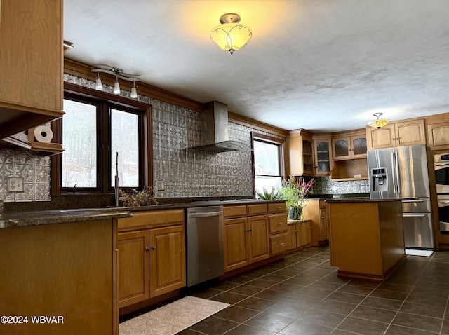 kitchen featuring backsplash, wall chimney exhaust hood, stainless steel appliances, dark tile patterned floors, and a center island