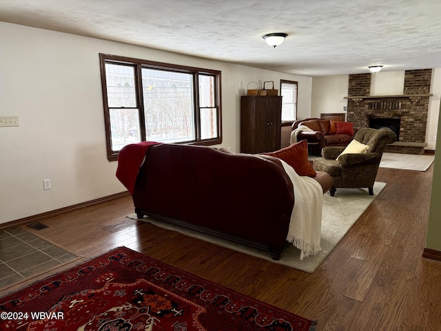 living room featuring a textured ceiling, dark hardwood / wood-style flooring, and a fireplace