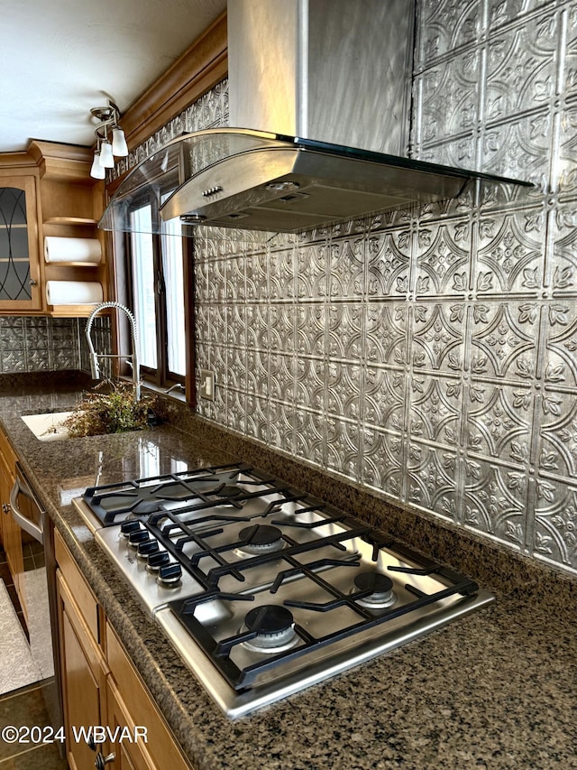 kitchen with appliances with stainless steel finishes, dark stone countertops, wall chimney exhaust hood, and sink