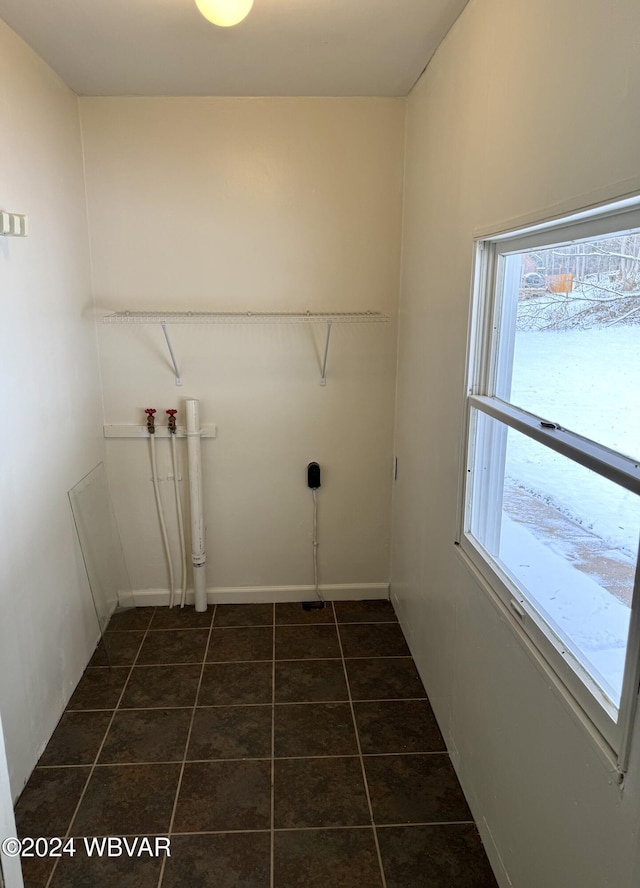 clothes washing area with dark tile patterned floors and hookup for a washing machine