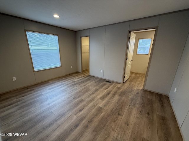 unfurnished bedroom featuring a walk in closet, a closet, and light hardwood / wood-style floors