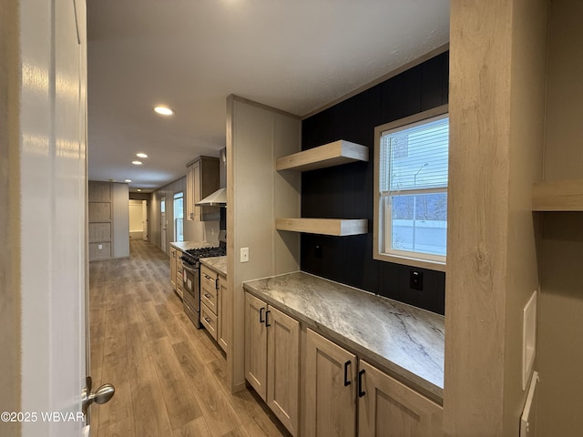 kitchen with light brown cabinetry, light hardwood / wood-style floors, range hood, and stainless steel range with gas stovetop