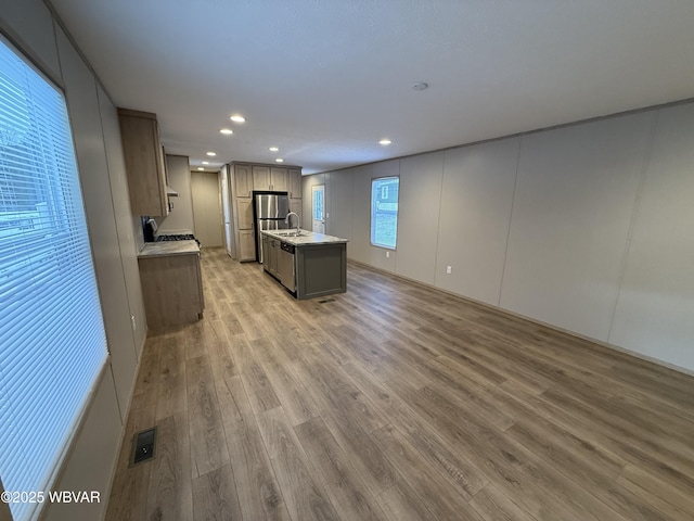 kitchen with gray cabinets, sink, light wood-type flooring, and a kitchen island with sink