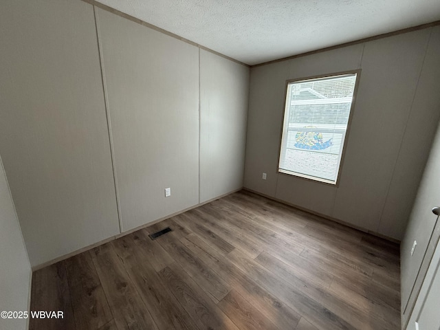 spare room featuring wood-type flooring and a textured ceiling