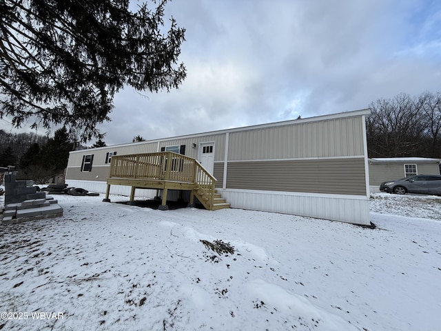 snow covered back of property with a wooden deck