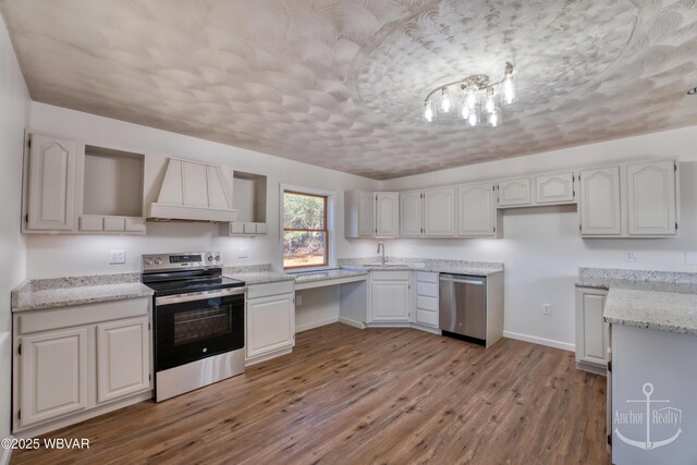 kitchen with appliances with stainless steel finishes, white cabinetry, light stone countertops, custom range hood, and light wood-type flooring