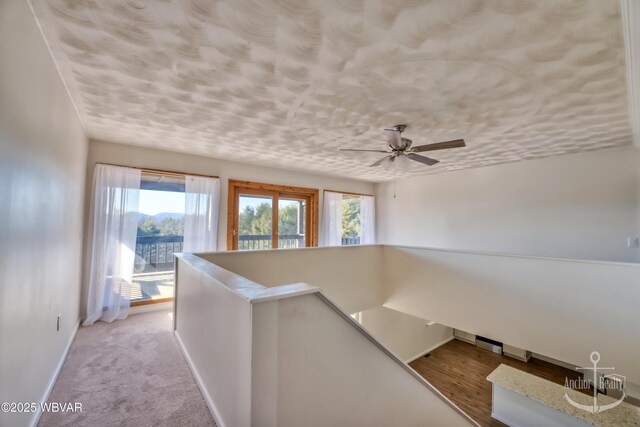 hallway with light colored carpet and a textured ceiling