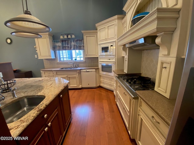 kitchen with dark hardwood / wood-style flooring, sink, extractor fan, white appliances, and decorative backsplash