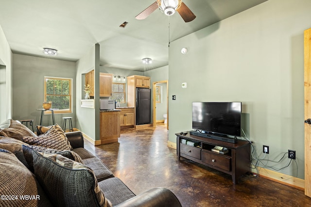 living area featuring a ceiling fan, baseboards, and concrete flooring