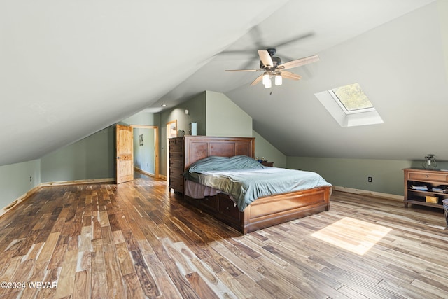 bedroom featuring lofted ceiling with skylight, wood finished floors, a ceiling fan, and baseboards