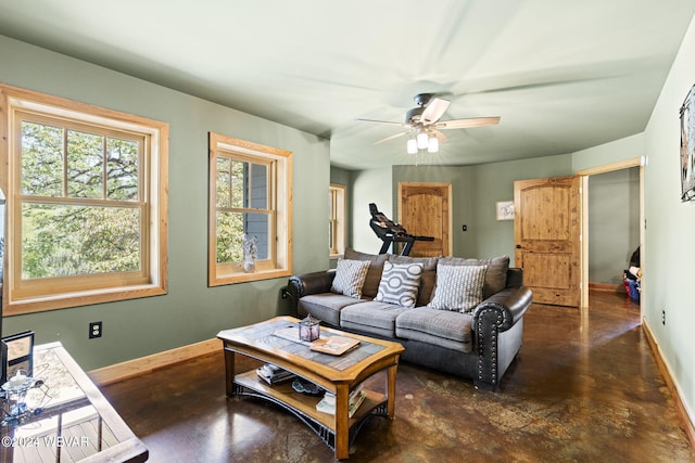 living area with concrete flooring, ceiling fan, and baseboards