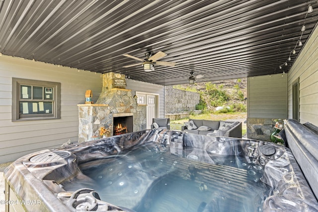 exterior space with a hot tub, ceiling fan, and an outdoor stone fireplace