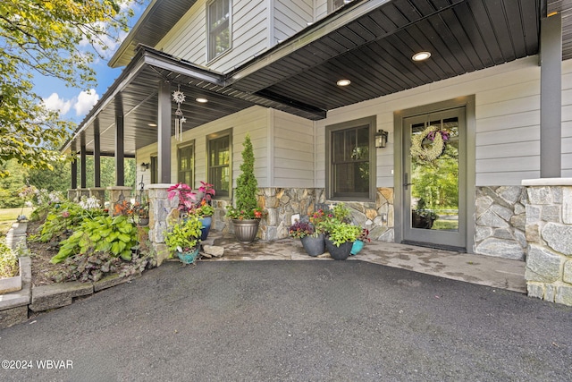 view of exterior entry with a porch and stone siding