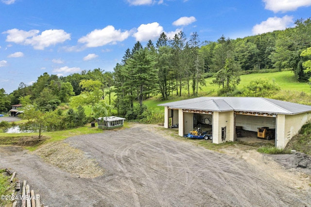 garage with driveway, a forest view, and a detached garage