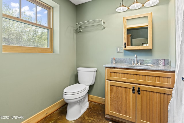 half bath with vanity, toilet, and baseboards