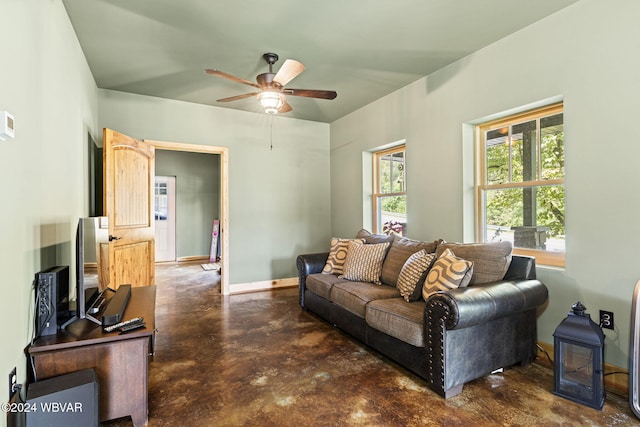 living room with concrete flooring, a ceiling fan, and baseboards