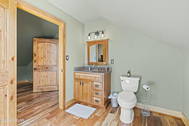 bathroom with lofted ceiling, vanity, toilet, and wood finished floors