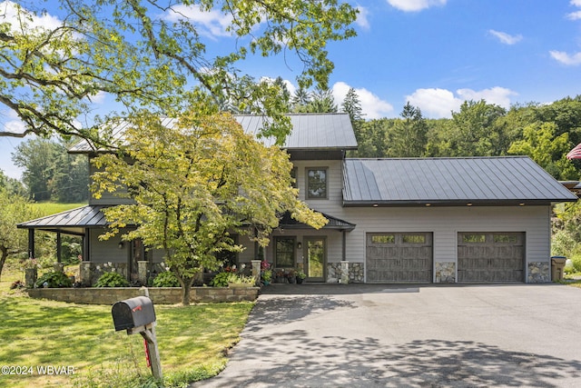 view of front facade with a standing seam roof, metal roof, a garage, driveway, and a front lawn