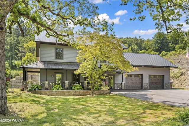 view of front facade featuring driveway, a porch, metal roof, an attached garage, and a front lawn