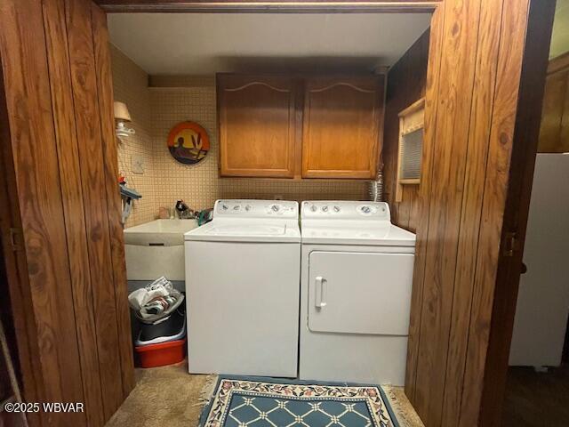 laundry area with washing machine and clothes dryer, sink, and cabinets