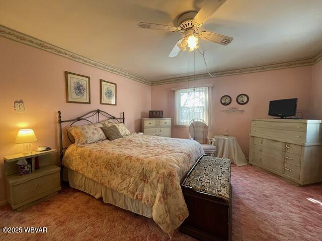 carpeted bedroom featuring ceiling fan and ornamental molding