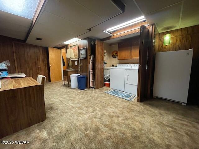 basement with wood walls, independent washer and dryer, white refrigerator, and carpet floors