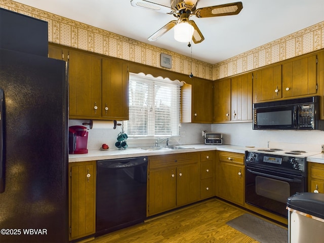 kitchen featuring black appliances, ceiling fan, dark hardwood / wood-style flooring, and sink