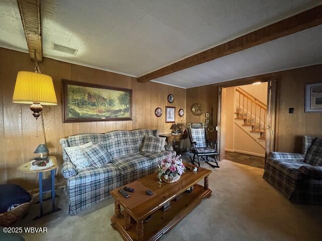 carpeted living room with wooden walls and beamed ceiling