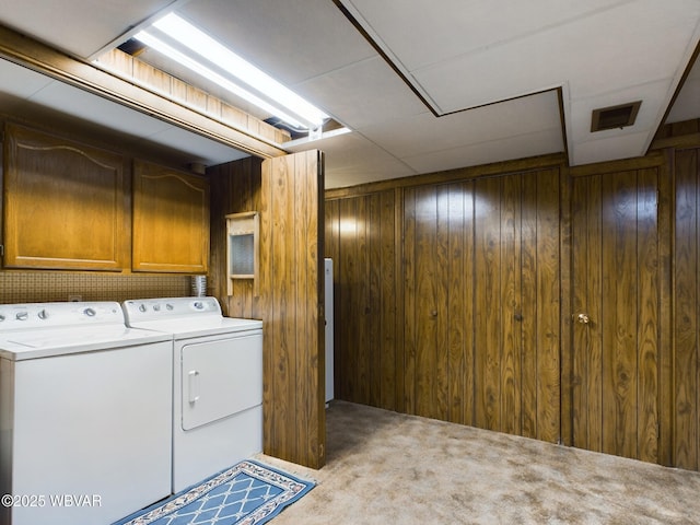 washroom featuring carpet, washer and clothes dryer, and wood walls