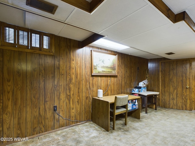 basement featuring light carpet and wooden walls