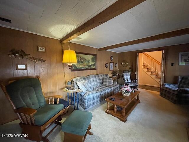 living room with carpet flooring, wooden walls, crown molding, and beamed ceiling