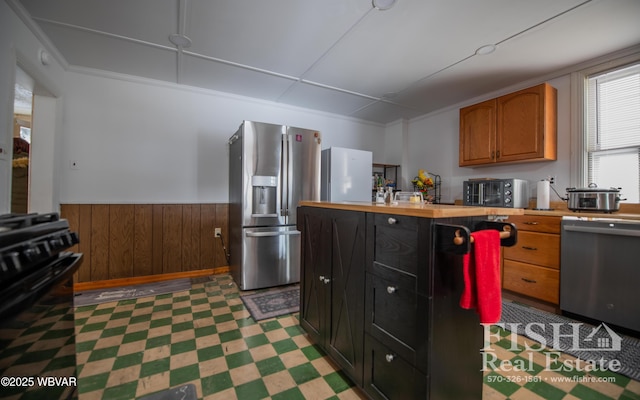 kitchen featuring wooden walls and appliances with stainless steel finishes