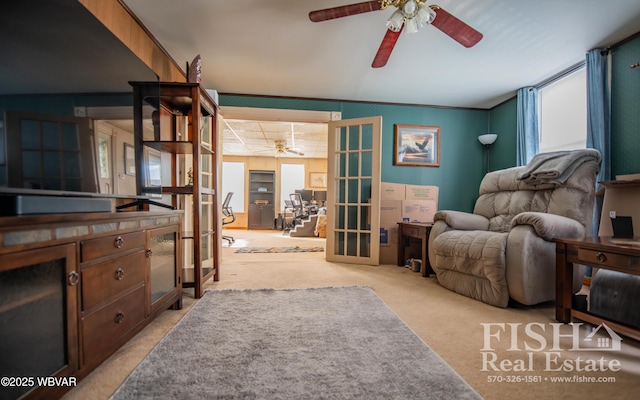 interior space with ornamental molding, ceiling fan, french doors, and light colored carpet