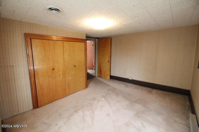 unfurnished bedroom with light carpet, a closet, and a textured ceiling