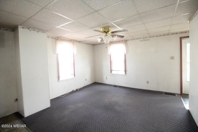 empty room featuring dark colored carpet, a paneled ceiling, and ceiling fan